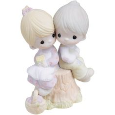 a figurine of two children sitting on top of a tree stump with their arms around each other