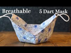 a paper boat sitting on top of a wooden table with the words breathable 5 darts mask