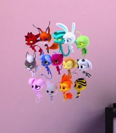 a bunch of littlest pet toys are hanging from the ceiling in a room with pink walls