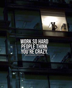 a man standing in the window of a tall building with a quote on it that reads, work so hard people think you're crazy