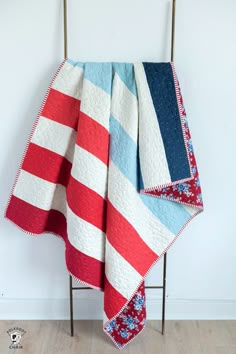 a red, white and blue quilted blanket on a chair next to a wall