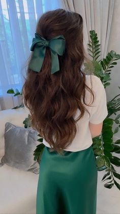 the back of a woman's head wearing a green satin skirt with a bow