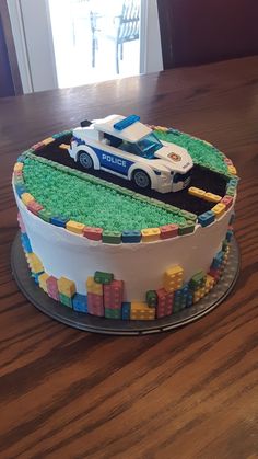 a birthday cake with a police car on the top and lego blocks in the middle