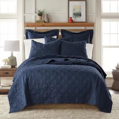 a bed in a bedroom with blue comforter and pillows