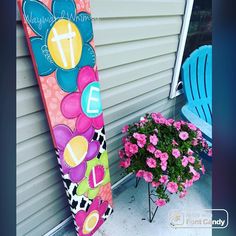 a colorful surfboard sitting on the side of a house next to a potted plant