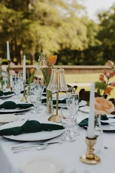 the table is set with place settings and flowers in vases, candlesticks, and napkins