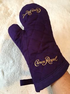 a purple oven mitt sitting on top of a white towel next to a person's hand