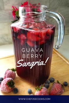 a jar filled with liquid sitting on top of a wooden cutting board next to strawberries