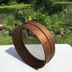 a wooden sculpture sitting on top of a white table in front of some flowers and rocks