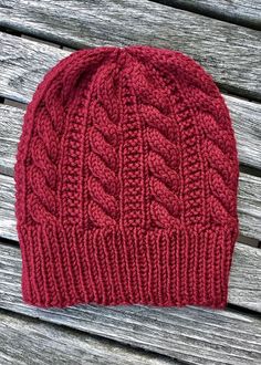 a red knitted hat sitting on top of a wooden bench