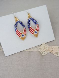 the american flag beaded earrings are displayed on a piece of paper next to lace