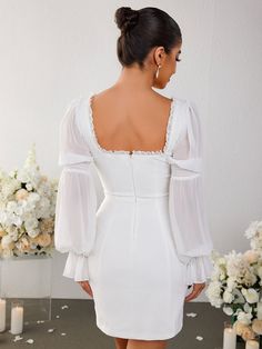 the back of a woman wearing a white dress with long sleeves and ruffles