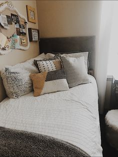 a bed with many pillows on it in a room next to a window and pictures