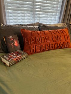 an orange pillow and some books on a bed