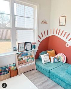 a living room with a blue couch and bookshelf next to a large window