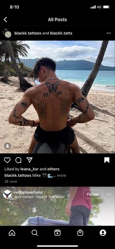 the back of a man with tattoos on his chest sitting in front of a beach