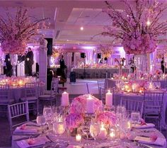 the tables are set with candles and centerpieces for an elegant wedding reception in purple hues