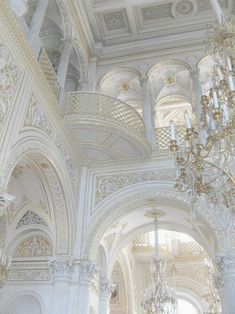 an ornate white building with chandeliers hanging from it's ceiling and walls