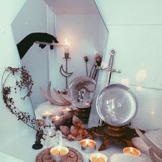 candles are sitting on the floor in front of a mirror and other items that have been placed around it