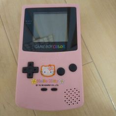 a pink game boy color sitting on top of a wooden floor