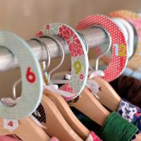 several wooden clothes hangers with different designs and colors hanging on metal rods in a row