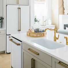 a kitchen with white cabinets and gold handles