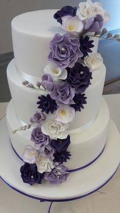 a wedding cake with purple and white flowers on top