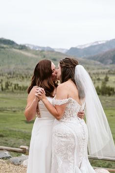 two women in wedding dresses kissing each other