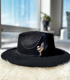 This 100% Australian Wool Fedora Hat features a triangle crystal chain that drapes beautifully down the crown, catching the light with every movement. A soft suede hat band adds a refined touch, while a stunning feather, finished with a micro pave bead, adds delicate charm. Two crystal rivets on the crown complete the look, offering a subtle sparkle finish.  Invisible Velcro tab on the inner band to adjust 2 cm smaller Structured hat Ultra stiff brim Small 56cm S/M 58 cm  M/L 60 cm Crown: 4.75" | 12 cm Brim: 3" | 8 cm 100% Australian Wool Elegant Felt Hat With Feathers And Flat Brim, Winter Adjustable Fedora With Feathers, Winter Fedora With Feathers And Adjustable Fit, Bohemian Winter Fedora For Party, Bohemian Winter Party Fedora, Elegant Feathered Fedora Felt Hat, Elegant Fedora Felt Hat With Feathers, Elegant Wide Brim Felt Hat With Feathers, Bohemian Party Hat With Feathers