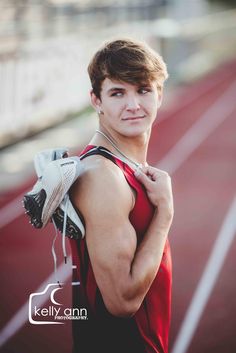 a young man is standing on a track with his arm around his shoulder and holding a pair of gloves