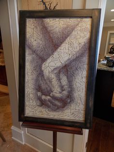 a couple holding hands in front of a framed photo with words written on the paper