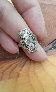 a woman's hand with a ring on it that has diamonds and emeralds