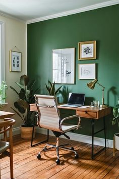 a home office with green walls and wooden flooring in the corner, along with potted plants