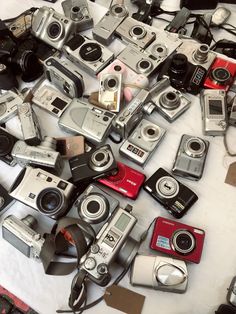 many different types of cameras are on the table with white cloths and tags around them