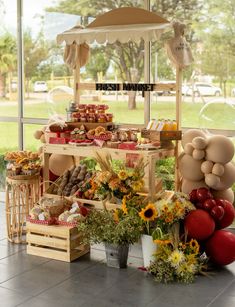 an outdoor food stand with sunflowers and balloons