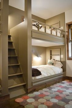 a bedroom with bunk beds and stairs leading up to the top floor, along with a rug on the floor