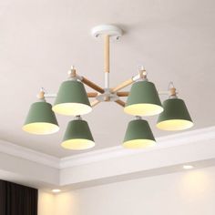 four green lamps hanging from the ceiling in a room with white walls and black curtains