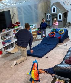 a man and two children playing in a playroom