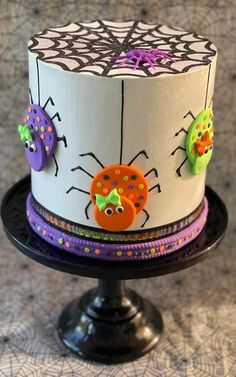 a decorated cake on top of a black plate with purple, green and orange decorations