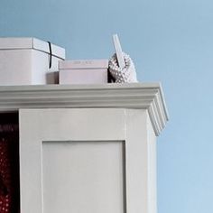 an open white cabinet with red and white items on the top, in front of a blue wall