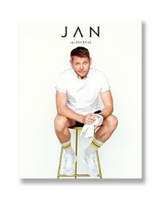 a man sitting on top of a stool next to a white wall with the cover of jan magazine