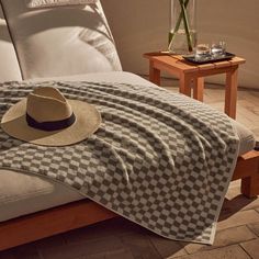 a hat on top of a bed next to a glass vase with flowers in it