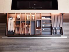 a kitchen drawer with utensils and silverware in it, under a flat screen tv