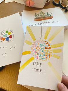 two handmade greeting cards sitting on top of a table next to a coffee cup