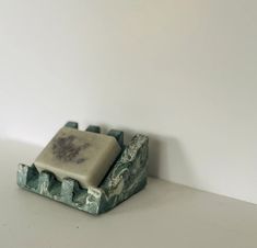 a soap dish sitting on top of a white counter next to a gray and black object