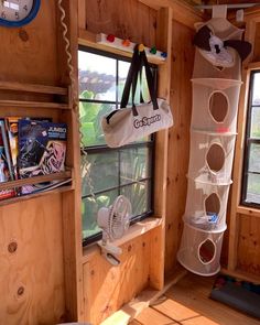 the inside of a small wooden cabin with windows and shelves filled with books, magazines and toys