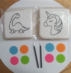 two decorated cookies sitting on top of a plate next to some markers and stickers