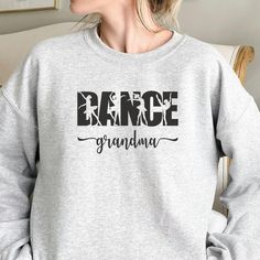 a woman wearing a grey sweatshirt with the word dance grandma printed in black on it