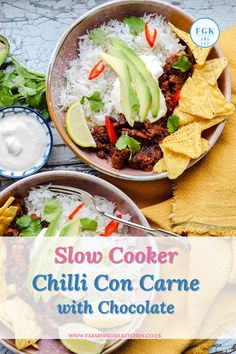 two bowls filled with chili con carne and topped with avocado, sour cream and tortilla chips