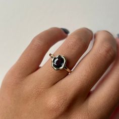 a woman's hand wearing a gold ring with a black stone in the middle